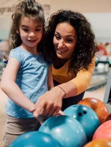 Adult with child choosing ten pin bowling balls