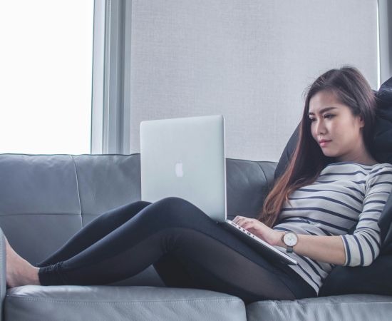 Woman lying on sofa looking at computer